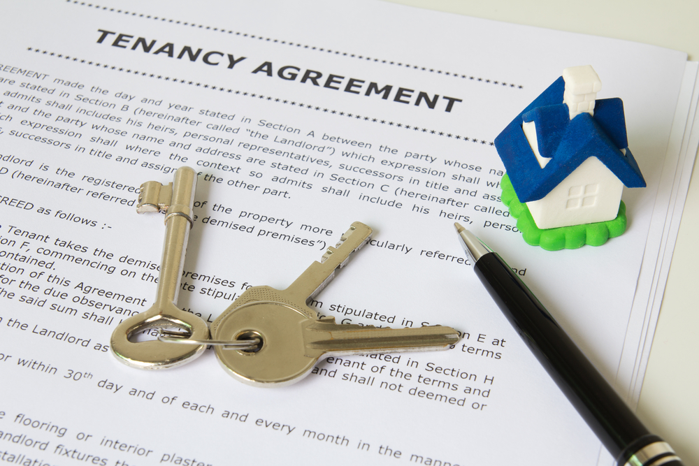 Tenancy agreement, key and pen with symbolic miniature house